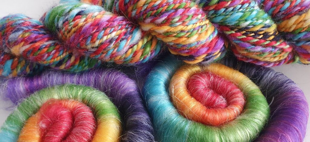 A collection of vibrant, multicolored yarns and rolags arranged artistically